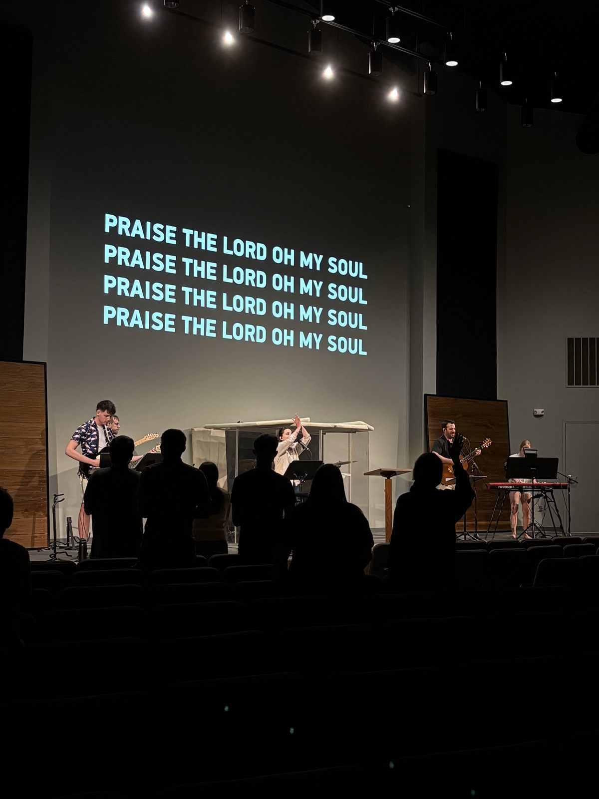 The band leads as the congregation sings, lyrics on the wall